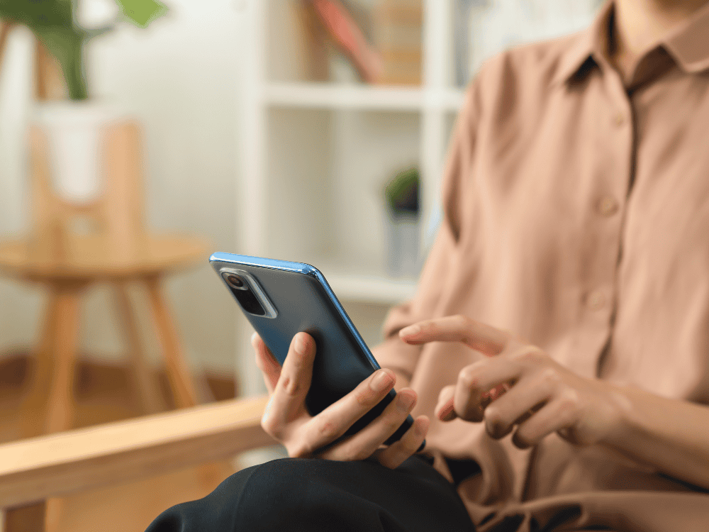 Woman writing on a note pad in front of a laptop